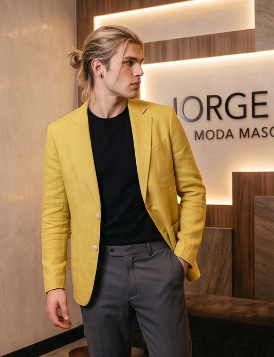 blazer de lino desestructurado para hombre. La prenda, de corte casual y ligero, muestra la textura granulada natural del lino. Tiene solapas de muesca, un cierre de dos botones frontales y dos grandes bolsillos de parche aplicados en la cintura.