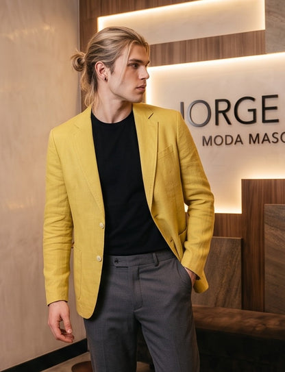 blazer de lino desestructurado para hombre. La prenda, de corte casual y ligero, muestra la textura granulada natural del lino. Tiene solapas de muesca, un cierre de dos botones frontales y dos grandes bolsillos de parche aplicados en la cintura.