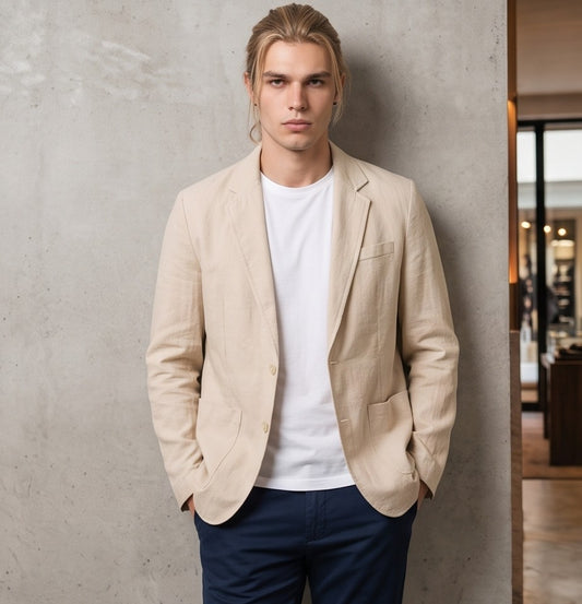 blazer de lino desestructurado para hombre. La prenda, de corte casual y ligero, muestra la textura granulada natural del lino. Tiene solapas de muesca, un cierre de dos botones frontales y dos grandes bolsillos de parche aplicados en la cintura.