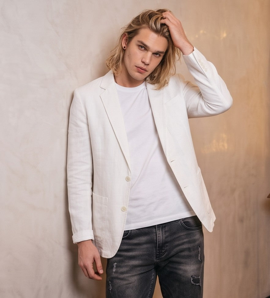 blazer de lino desestructurado para hombre. La prenda, de corte casual y ligero, muestra la textura granulada natural del lino. Tiene solapas de muesca, un cierre de dos botones frontales y dos grandes bolsillos de parche aplicados en la cintura.