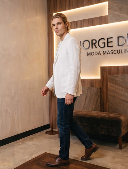 blazer de lino desestructurado para hombre. La prenda, de corte casual y ligero, muestra la textura granulada natural del lino. Tiene solapas de muesca, un cierre de dos botones frontales y dos grandes bolsillos de parche aplicados en la cintura.