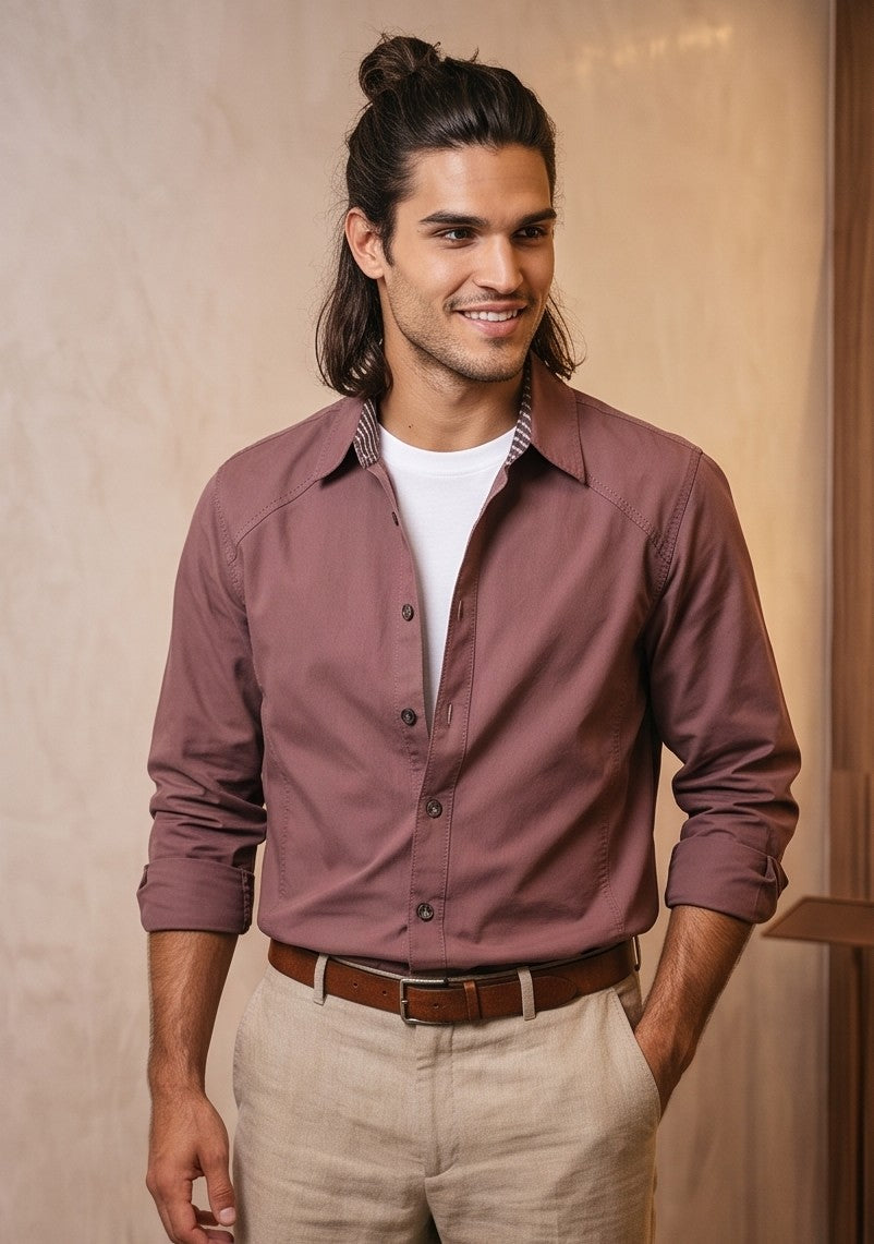 Camisa casual de hombre confeccionada en algodón liso, de corte holgado y manga larga, con cuello de solapa camisero abotonado al frente y detalle estampado en el borde interno de los puños y cuello, mostrada de frente y de espaldas en tonos café rojizo y gris oscuro azulado.