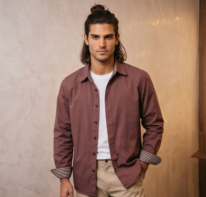 Camisa casual de hombre confeccionada en algodón liso, de corte holgado y manga larga, con cuello de solapa camisero abotonado al frente y detalle estampado en el borde interno de los puños y cuello, mostrada de frente y de espaldas en tonos café rojizo y gris oscuro azulado.