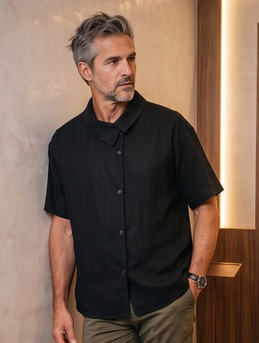 Camisa casual de manga corta holgada para hombre con textura ligera tipo lino, cuello asimétrico y botones frontales, disponible en color negro y beige arena sobre fondo neutro