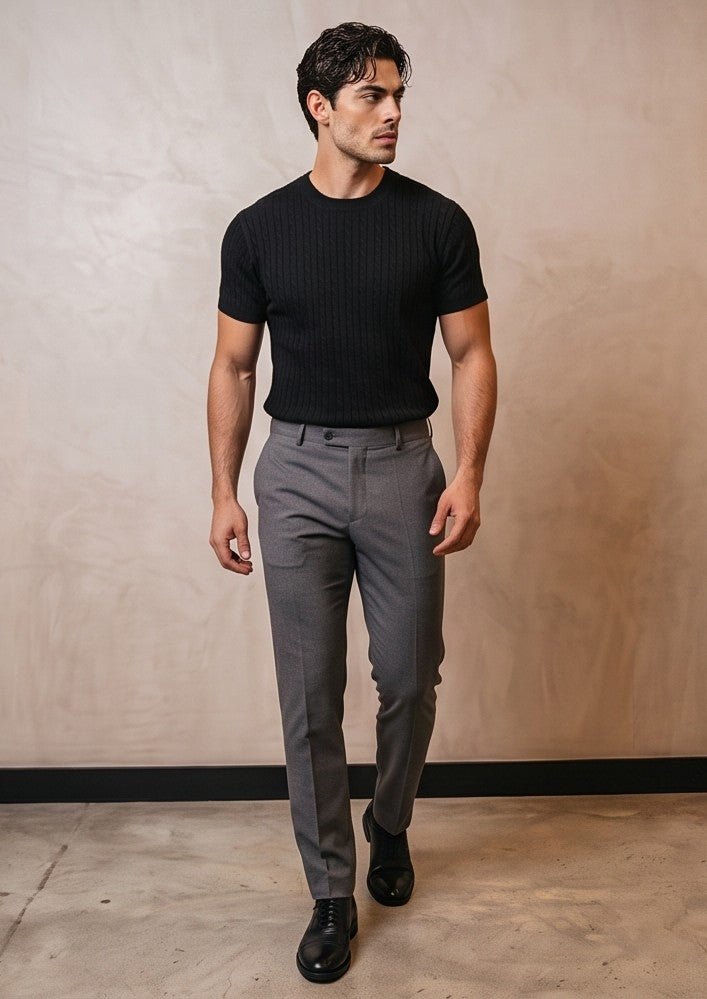 Hombre luciendo una camiseta de punto trenzado de manga corta y cuello redondo. Diseño de textura en relieve con ajuste entallado que resalta la figura masculina. Prenda de estilo smart-casual, disponible en colores neutros y versátiles (beige, blanco y negro), combinada con diferentes pantalones para un look moderno y elegante