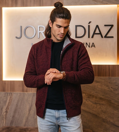 Cárdigan de punto grueso para hombre con cuello alto, cierre de cremallera metálica y forro interior de cuadros escoceses, disponible en negro, gris oscuro jaspeado, azul jaspeado y rojo burdeos jaspeado, exhibido en una tienda de moda masculina