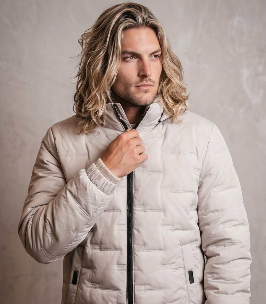 Chaqueta acolchada para hombre de corte holgado con capucha, cremallera frontal y textura geométrica termosellada, disponible en tonos beige crema, azul grisáceo y negro