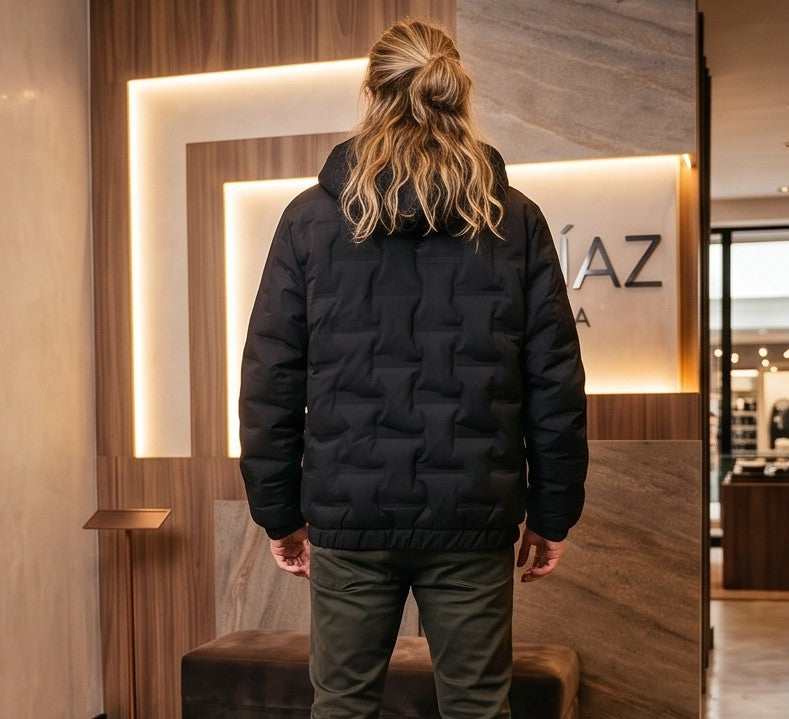 Chaqueta acolchada para hombre de corte holgado con capucha, cremallera frontal y textura geométrica termosellada, disponible en tonos beige crema, azul grisáceo y negro