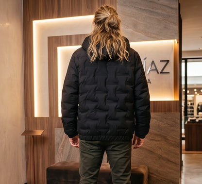 Chaqueta acolchada para hombre de corte holgado con capucha, cremallera frontal y textura geométrica termosellada, disponible en tonos beige crema, azul grisáceo y negro