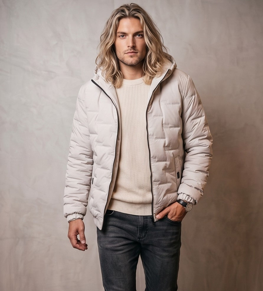Chaqueta acolchada para hombre de corte holgado con capucha, cremallera frontal y textura geométrica termosellada, disponible en tonos beige crema, azul grisáceo y negro