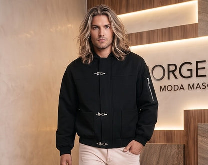 Chaqueta bomber para hombre con capucha, confeccionada en tejido liso disponible en color negro y azul marino, con bolsillos delanteros, bolsillo utilitario con cremallera plateada en la manga, bajo elástico fruncido y cierres metálicos tipo mosquetón al frente