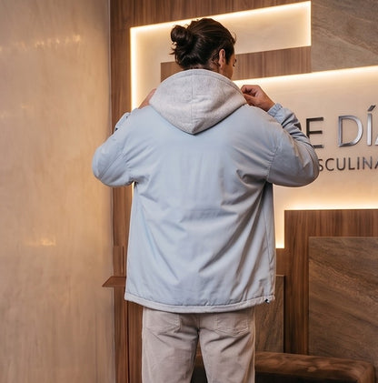 Chaqueta urbana estilo bomber oversize con capucha y forro interior a contraste efecto dos piezas con cierre de cremallera frontal, cuello camisero con solapa, puños elásticos y bajo recto. Disponible en combinaciones de color negro con azul, beige caqui con azul y celeste con gris.
