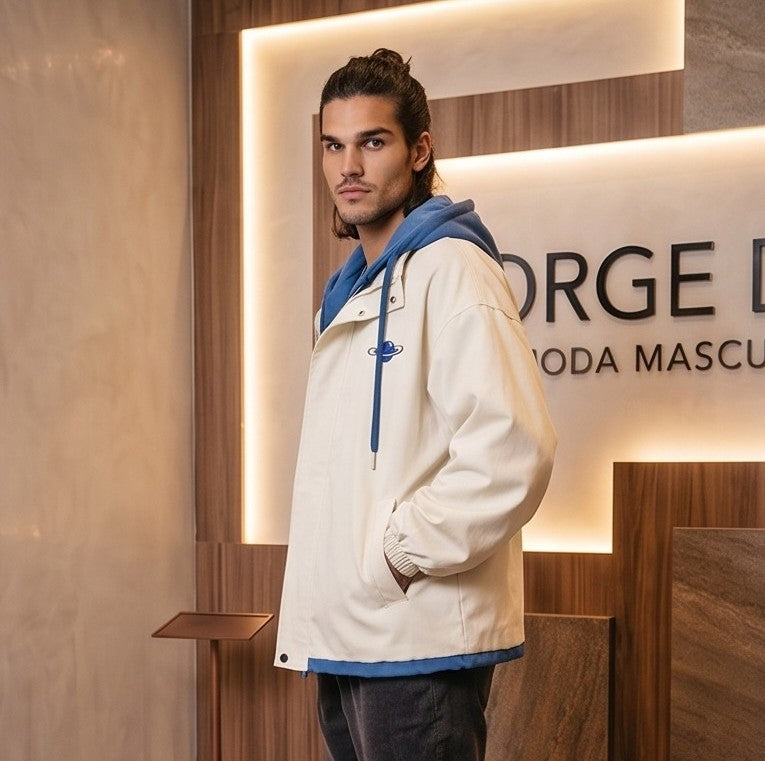 Chaqueta urbana estilo bomber oversize con capucha y forro interior a contraste efecto dos piezas con cierre de cremallera frontal, cuello camisero con solapa, puños elásticos y bajo recto. Disponible en combinaciones de color negro con azul, beige caqui con azul y celeste con gris.