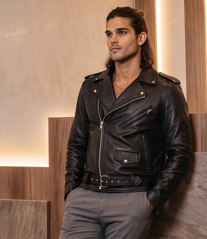 Chaqueta de cuero estilo biker para hombre con solapas cruzadas, cremalleras metálicas asimétricas, bolsillos frontales y cinturón ajustable con hebilla, disponible en color negro y rojo brillante.
