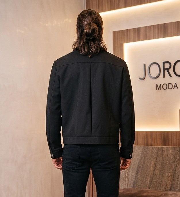 Chaqueta entallada slim fit para hombre disponible en color negro y azul marino, confeccionada en tejido liso estructurado con cuello camisero, cremallera metálica frontal central, puños con cierre a presión y detalles decorativos de solapa en los hombros sobre fondo de estudio minimalista