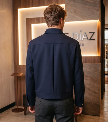 Chaqueta entallada slim fit para hombre disponible en color negro y azul marino, confeccionada en tejido liso estructurado con cuello camisero, cremallera metálica frontal central, puños con cierre a presión y detalles decorativos de solapa en los hombros sobre fondo de estudio minimalista