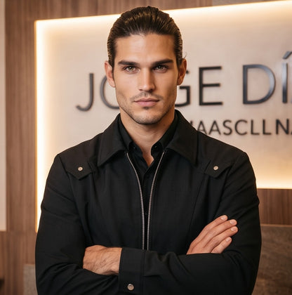 Chaqueta entallada slim fit para hombre disponible en color negro y azul marino, confeccionada en tejido liso estructurado con cuello camisero, cremallera metálica frontal central, puños con cierre a presión y detalles decorativos de solapa en los hombros sobre fondo de estudio minimalista