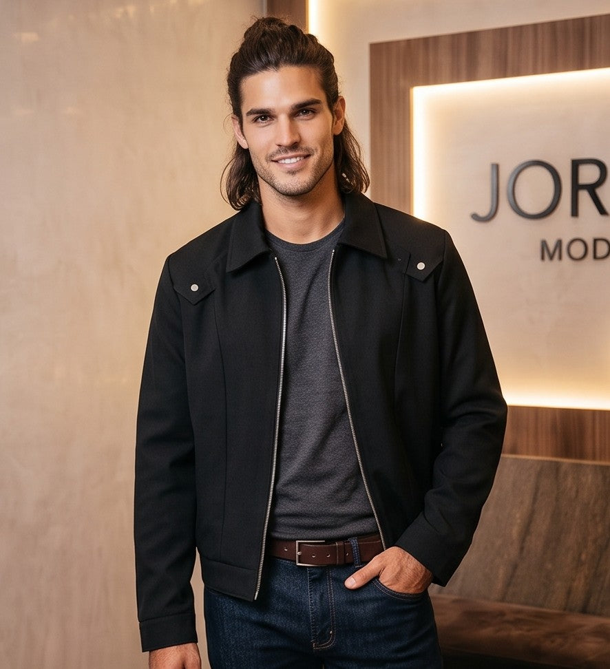 Chaqueta entallada slim fit para hombre disponible en color negro y azul marino, confeccionada en tejido liso estructurado con cuello camisero, cremallera metálica frontal central, puños con cierre a presión y detalles decorativos de solapa en los hombros sobre fondo de estudio minimalista