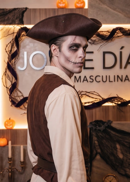 Disfraz de pirata para hombre y adulto que incluye camisa color marfil de manga larga con cuello en V, chaleco marrón con cinturón y fajín a rayas, pantalón a rayas verticales oscuras, cubrebotas marrones y sombrero de tres picos tradicional