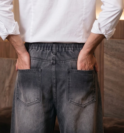 Pantalón vaquero de corte ancho y tiro medio en tono azul claro con efecto desgastado, costuras verticales decorativas en las piernas y detalle de cintura elástica en la parte trasera.