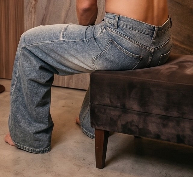 Pantalón vaquero de corte ancho y tiro medio en tono azul claro con efecto desgastado, costuras verticales decorativas en las piernas y detalle de cintura elástica en la parte trasera.