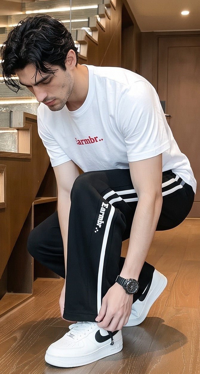 Pantalón jogger deportivo y casual para hombre de corte ancho y tiro medio, con cintura elástica con cordón ajustable, franjas laterales a contraste con detalle de texto estampado y bolsillos funcionales, disponible en color negro y gris jaspeado