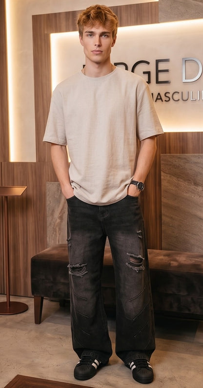 Pantalón jean ancho estilo urbano streetwear en denim 100% algodón con efecto lavado en tonos azul y negro desgastado, tiro medio-alto, cintura semielástica con botón y cremallera, roturas desgastadas en rodillas y bordados diagonales decorativos en las piernas