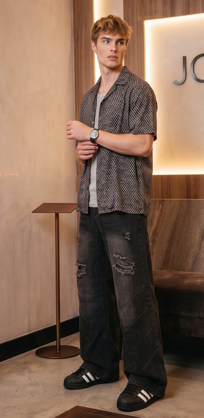 Pantalón jean ancho estilo urbano streetwear en denim 100% algodón con efecto lavado en tonos azul y negro desgastado, tiro medio-alto, cintura semielástica con botón y cremallera, roturas desgastadas en rodillas y bordados diagonales decorativos en las piernas