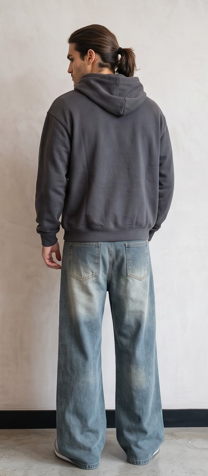 Pantalón jean ancho estilo urbano streetwear en denim 100% algodón con efecto lavado en tonos azul y negro desgastado, tiro medio-alto, cintura semielástica con botón y cremallera, roturas desgastadas en rodillas y bordados diagonales decorativos en las piernas