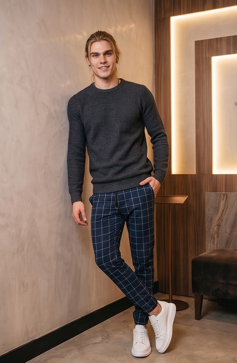 Pantalones estilo jogger para hombre con un elegante patrón de cuadros tipo ventana (windowpane grid). La prenda cuenta con una cintura elástica ajustable mediante cordón, bolsillos laterales prácticos y un ajuste ceñido pero cómodo que se estrecha hacia los tobillos. Está disponible en una gama de colores que incluye azul claro, beige, azul marino, gris oscuro y negro, todos con las líneas de los cuadros en contraste blanco.