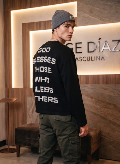 Sudadera de cuello redondo negra en corte holgado y estilo vintage urbano, con cruz roja desgastada y tipografía en el frontal, y mensaje tipográfico blanco en la espalda.