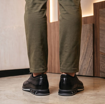 Zapatos híbridos de vestir y estilo casual para hombre con textura efecto piel de cocodrilo brillante, sistema de cordones elásticos ajustables con tanca y suela deportiva ergonómica antideslizante, disponibles en color negro, marrón café y gris degradado.