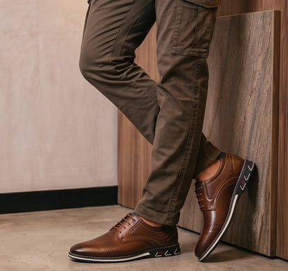 Zapatos oxford de hombre de cuero perforado en dos tonos, negro y marrón, con suela blanca y detalles de color en el talón.